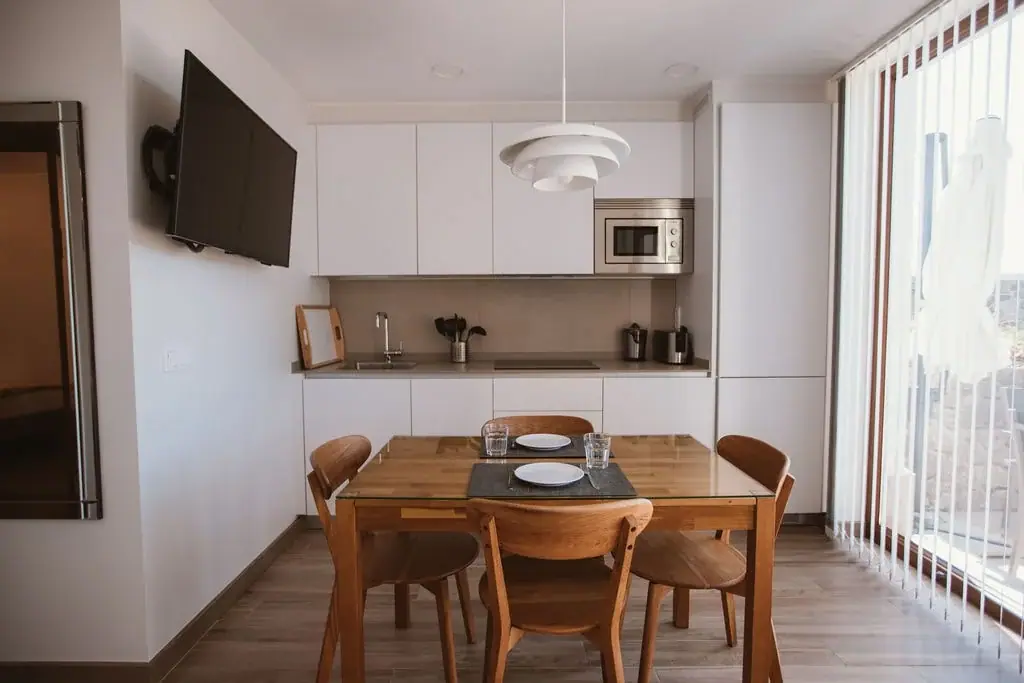 White kitchen with a microwave and a table for four in a Standard apartment