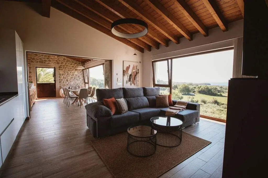 Living room of the Deluxe apartment with a stone wall and a picture window onto the meadow