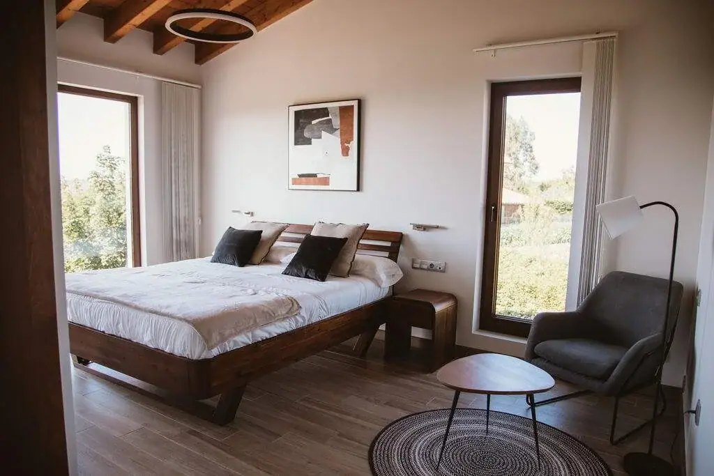 Main bedroom of the Deluxe apartment with a double bed, an armchair and large windows