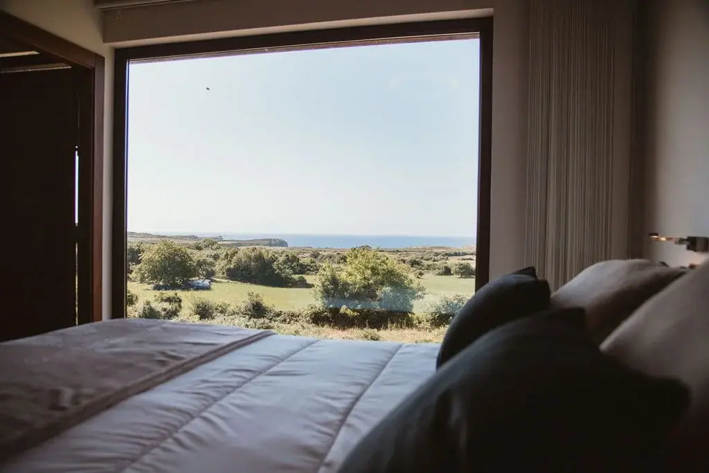 Bed facing the picture window of the Deluxe apartment, with the meadow and the sea