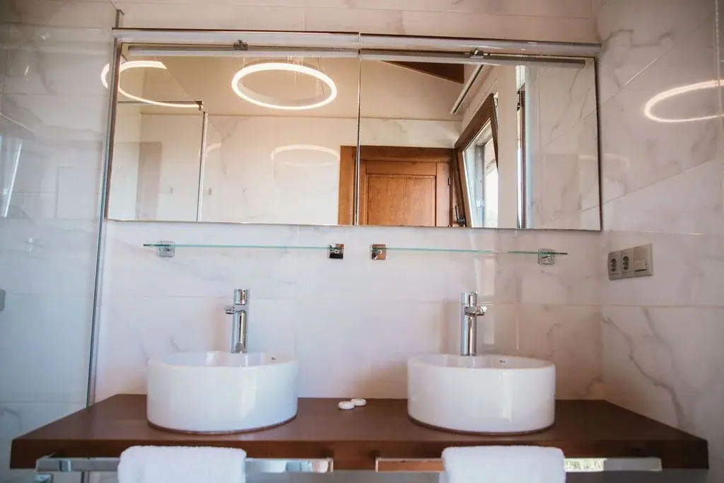 Double washbasins and a lit mirror in the bathroom of the Deluxe apartment