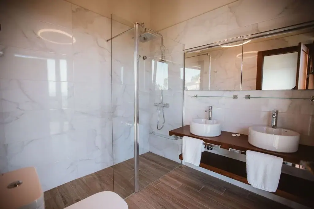 Bathroom of the Deluxe apartment with a glass shower and two washbasins