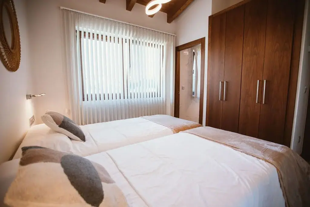 Twin bedroom with a wooden wardrobe in the Deluxe apartment