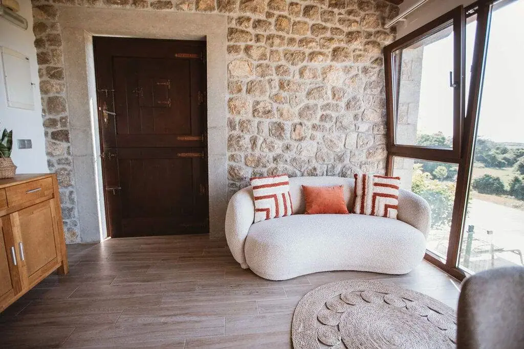 Corner with a curved sofa and a stone wall by the picture window of the Deluxe apartment