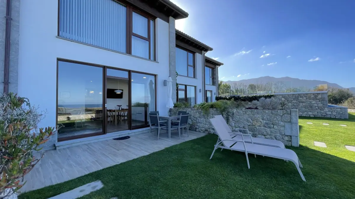 Front of the apartments with their garden and a sun lounger
