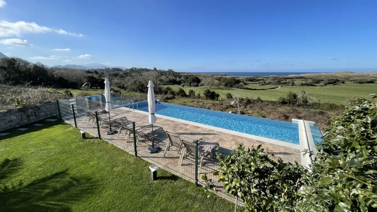 Infinity pool with sun loungers, the meadow and the sea beyond