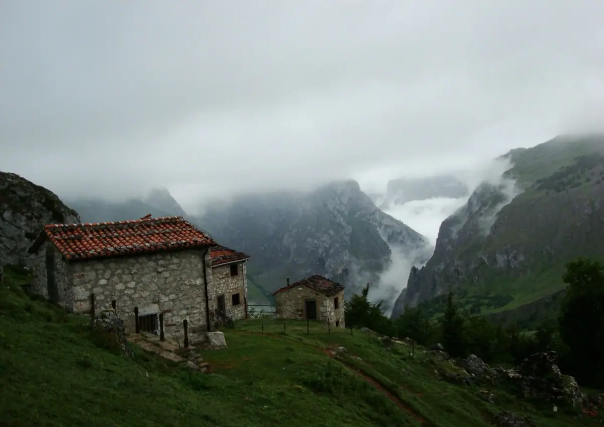 A stone hut and mountains in the mist