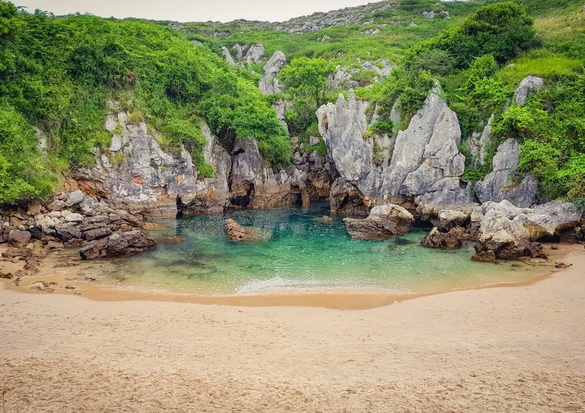 A sandy cove between green cliffs on the coast of Asturias