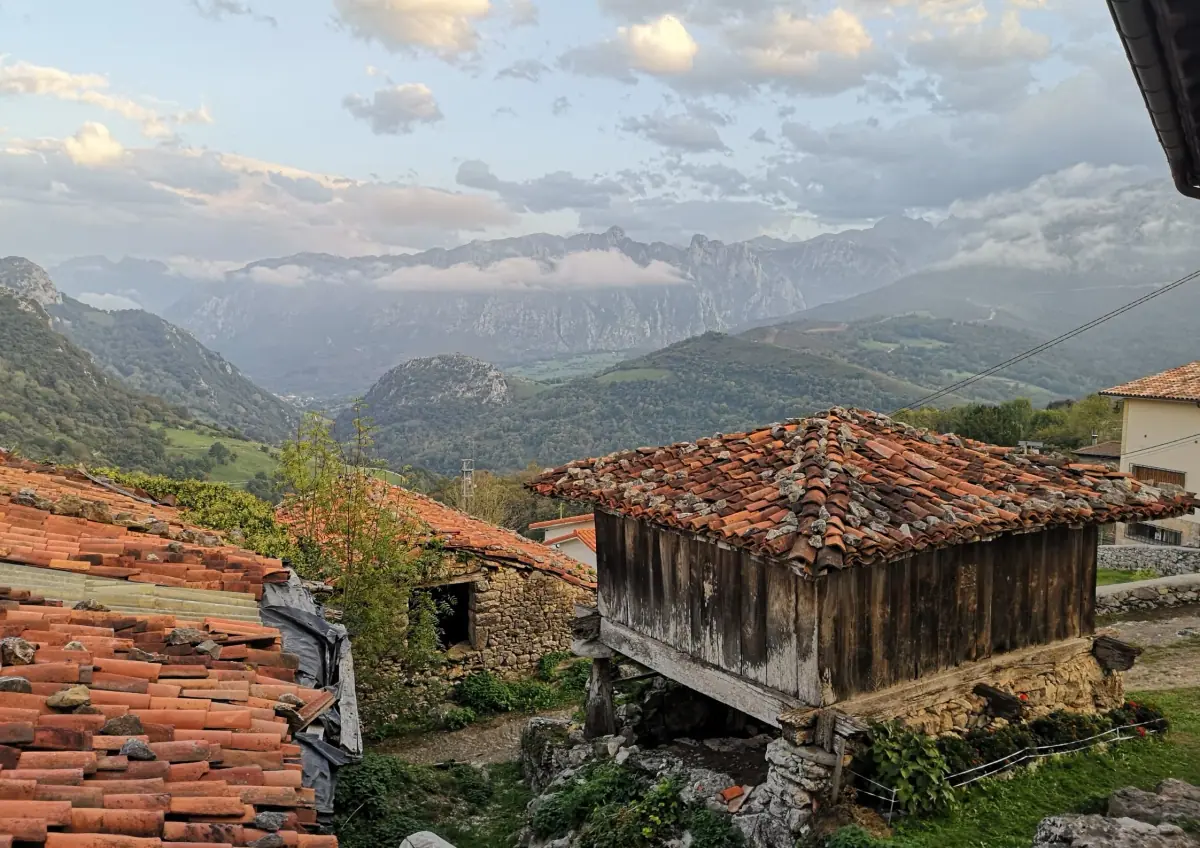 A hamlet with an hórreo and mountains behind