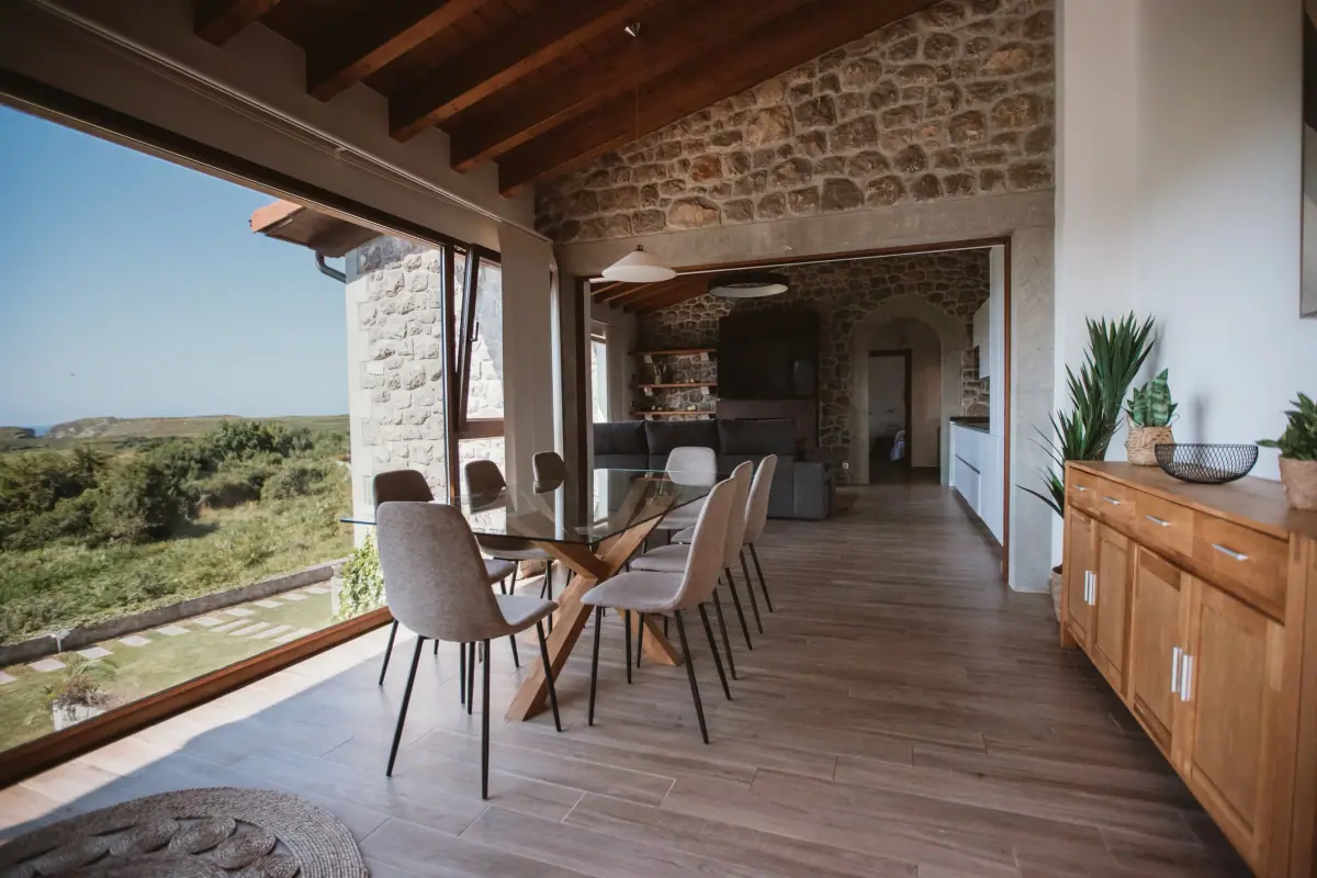 Dining room of the Deluxe apartment with a glass table and a picture window open to the meadow