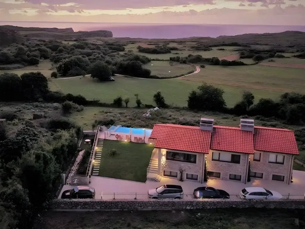 Aerial view of the Bufones de Pría apartments at sunset, among meadows and facing the sea