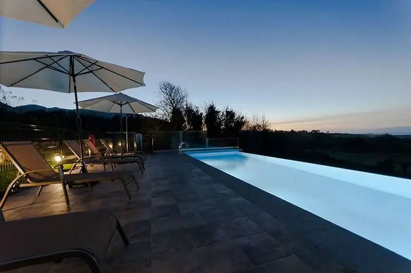 Infinity pool and terrace with parasols at dusk
