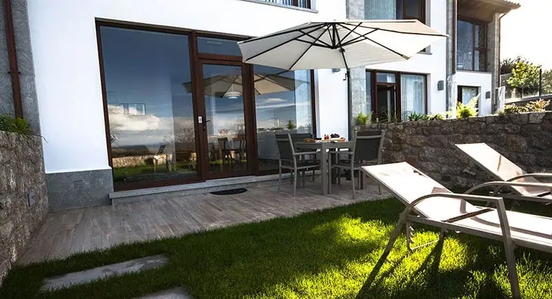 Terrace with sun loungers and a parasol in front of the apartments
