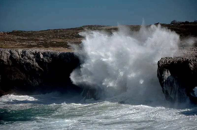 A wave crashing against the cliff