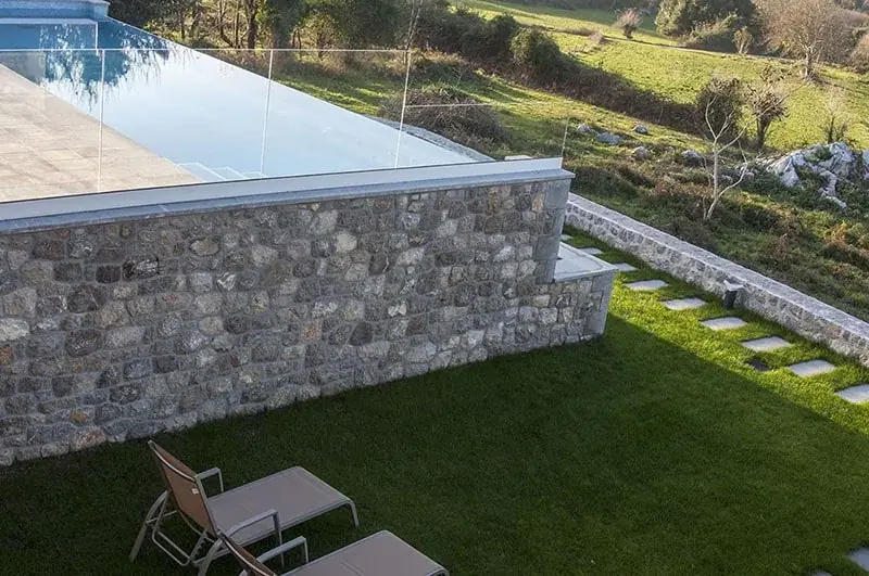 A stone wall and sun loungers in the garden