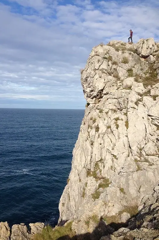 A walker on a rocky outcrop of the cliff, on the Asturian coast